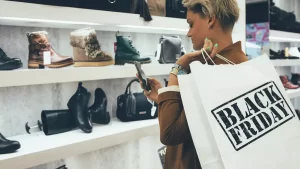 a women with mobile in hand shopping shoes on black Friday