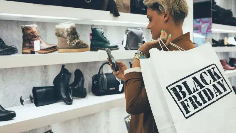 a women with mobile in hand shopping shoes on black Friday